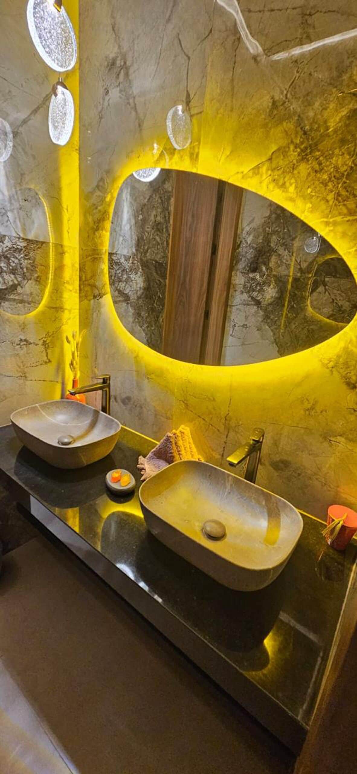 Un baño con dos lavamanos sobre encimera, un espejo y una pared con luz amarilla.