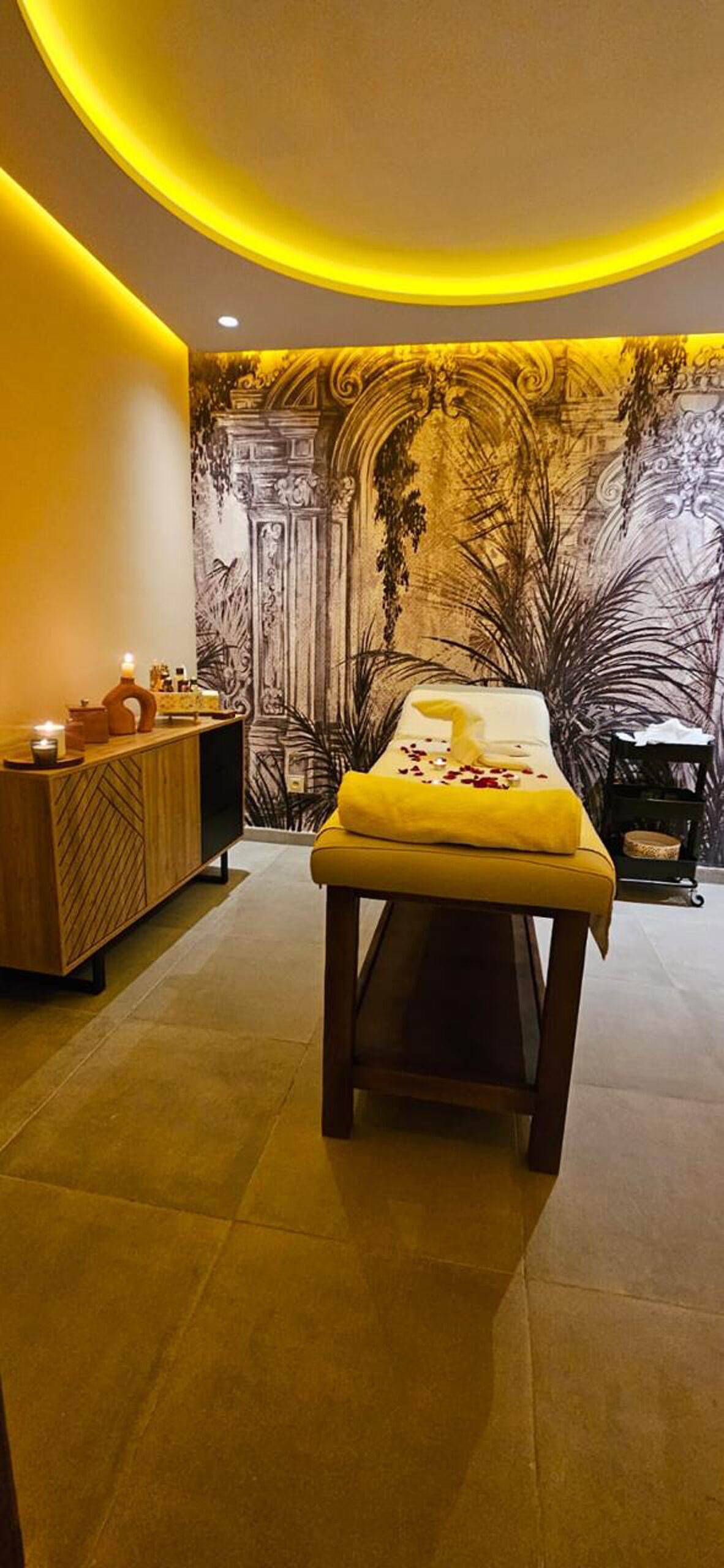 A room with a bed, a wooden cabinet, and a wall mural.