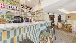 A bar area with shelves of liquor bottles, a coffee machine, stools, and a dartboard. - L'Ondée - apartment for 4 people - shared pool (Biscarrosse)