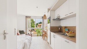 Une chambre d’hôtel moderne équipée d’un lit, d’une kitchenette, d’un coin repas et offrant une vue sur l’extérieur.