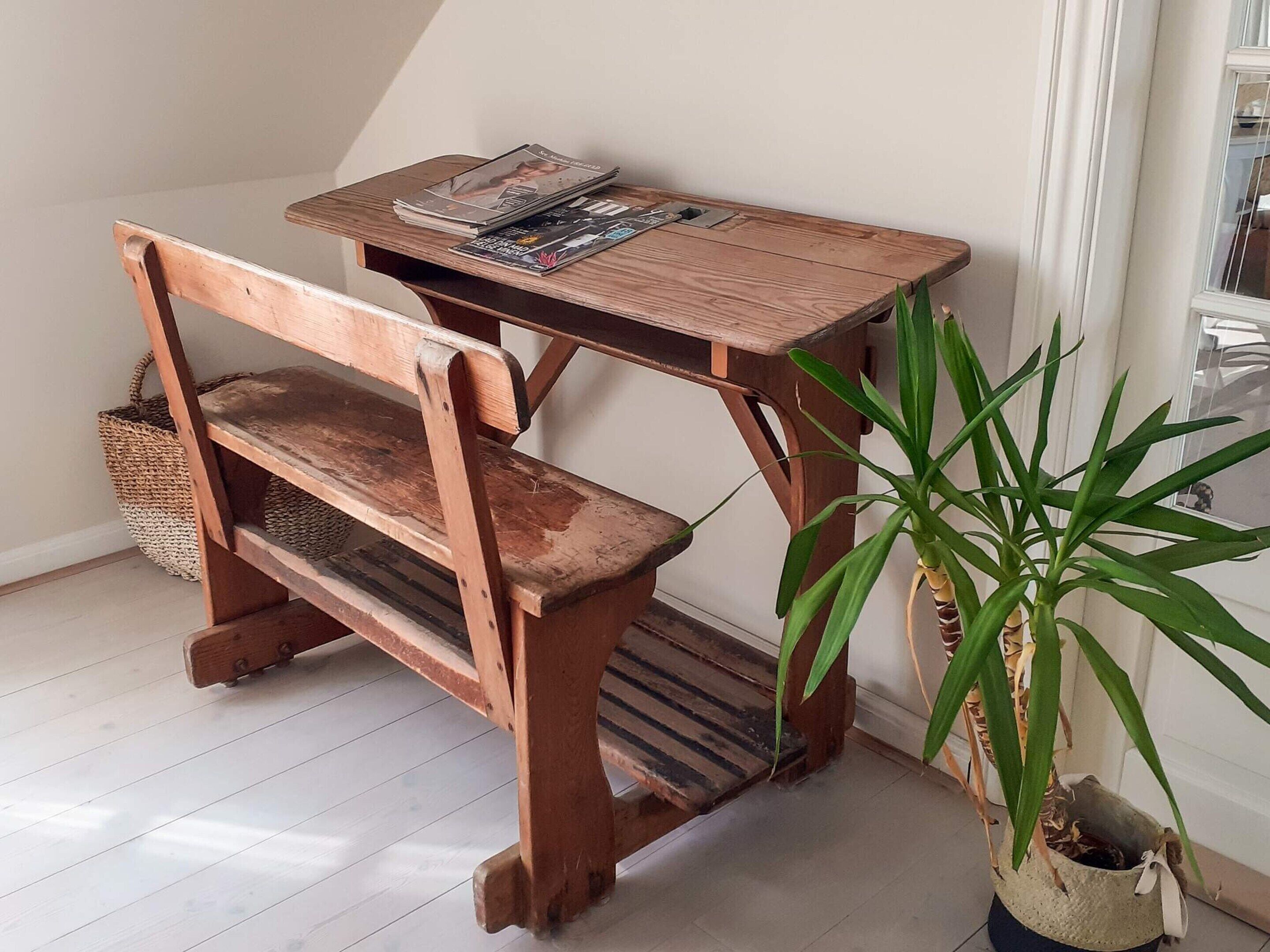 Um banco de madeira com mesa, um vaso de planta e uma janela com cortinas.