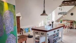 A kitchen with a wooden island, white cabinetry, and a colorful abstract painting. - 7 Person Holiday Home in Logstrup (Logstrup)