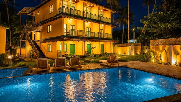 Un edificio de dos pisos con piscina, zona de estar al aire libre y una escalera que conduce al nivel superior.