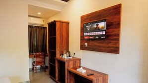 Una sala de estar moderna con una televisión de pantalla plana montada en una pared de madera, un mueble bajo para televisión de madera y una zona de estar con una silla y una mesita.
