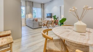 A modern living room with a sofa, dining table, chairs, and a TV. - Modern apartment near the marina - Estepona (Estepona)