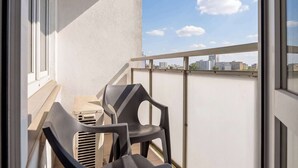 A balcony with two chairs, a table, and a view of the city skyline. - Modern Apartment with a Desk | Air Conditioning | Downtown (Warszawa)
