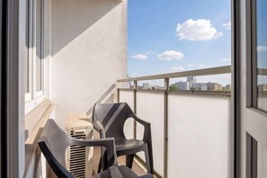 A balcony with two chairs, a table, and a view of the city skyline. - Modern Apartment with a Desk | Air Conditioning | Downtown (Warszawa)