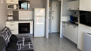 Et lille køkken med mikroovn, ovn, køleskab og en loftsvifte.