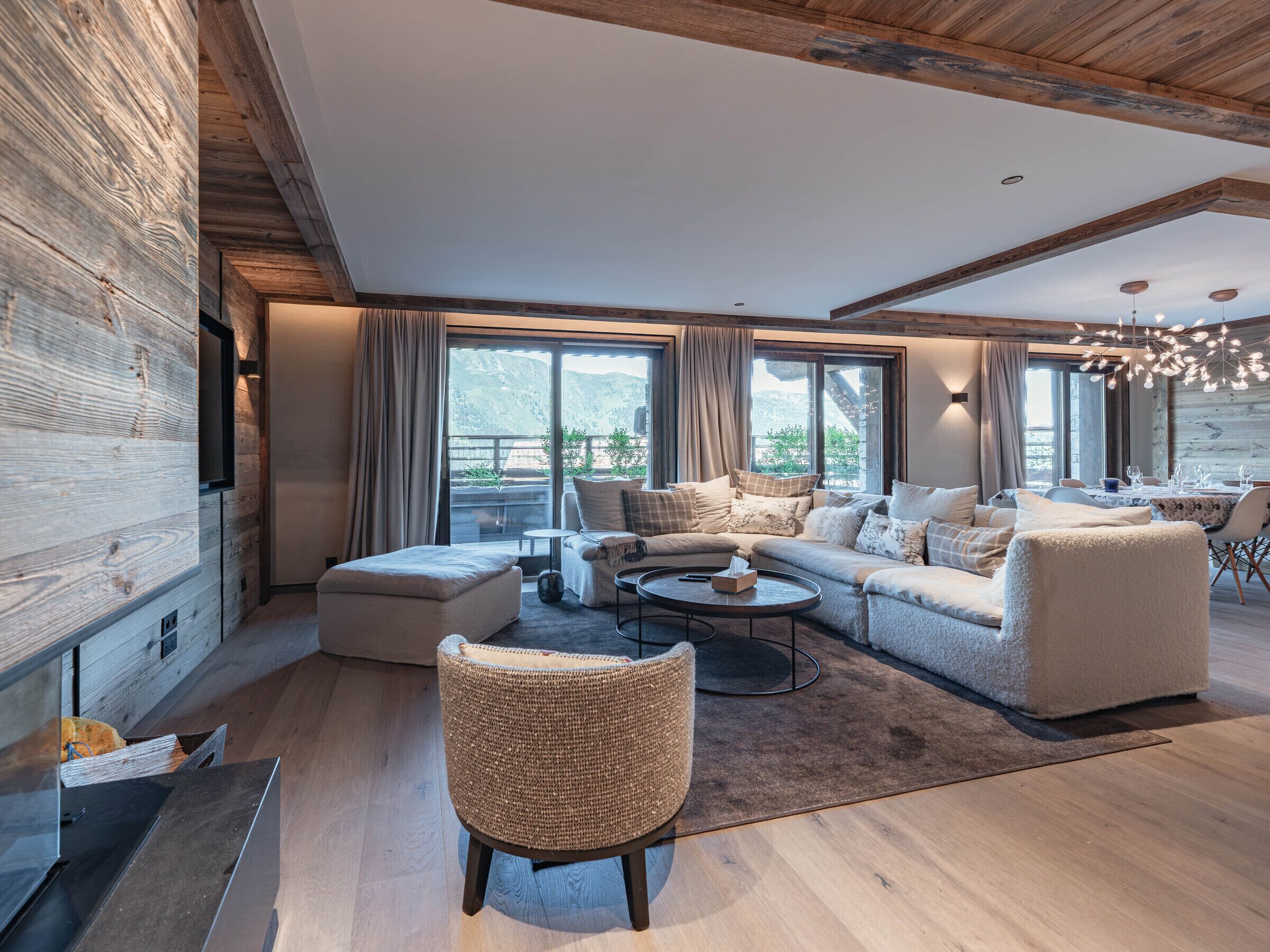 En moderne stue med sofa, lænestole, et sofabord og et spiseområde.