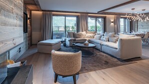 En moderne stue med sofa, lænestole, et sofabord og et spiseområde.