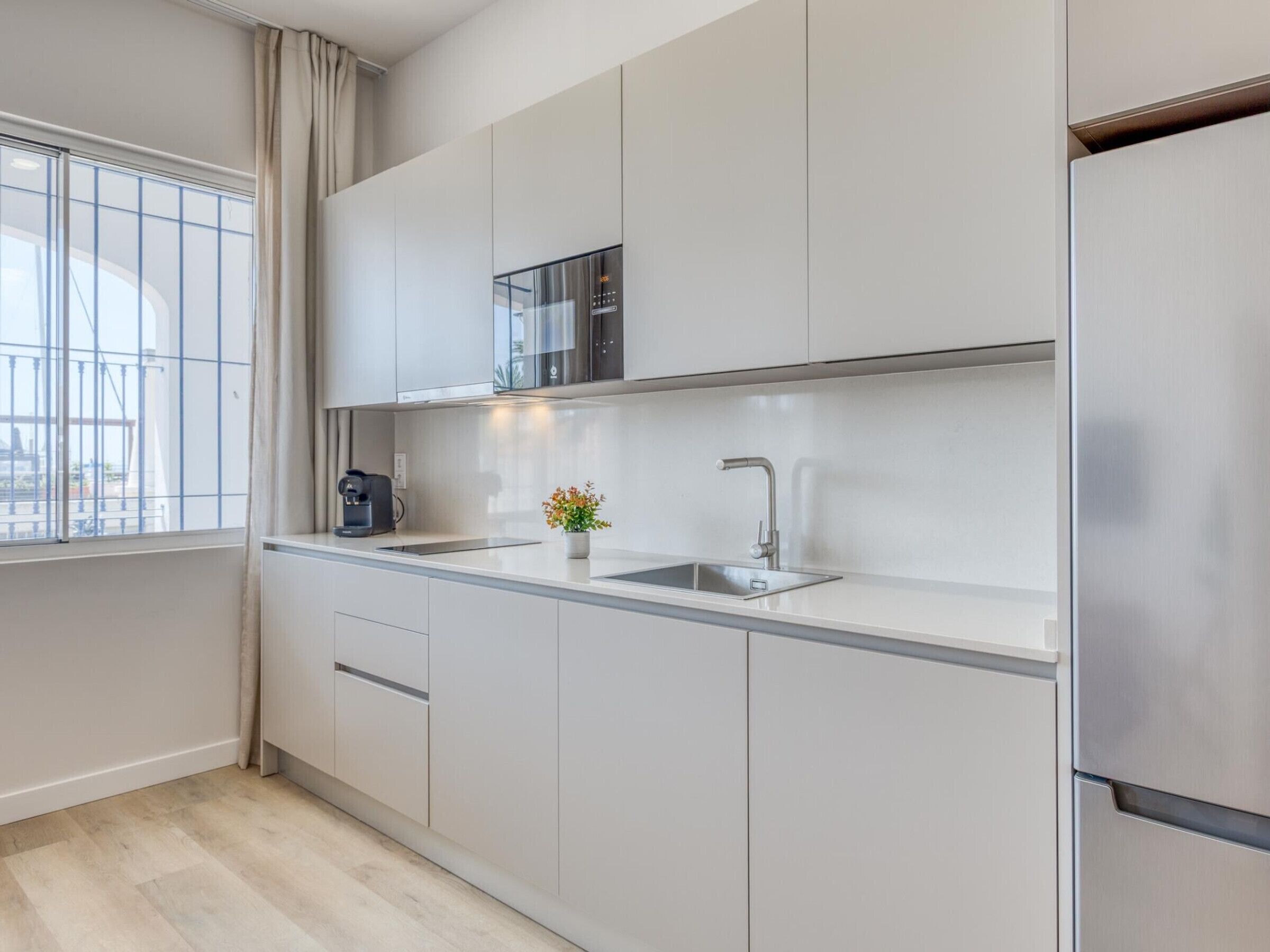 Eine moderne Küche mit einem Edelstahl-Kühlschrank, einer eingebauten Mikrowelle, einer Kaffeemaschine und einem Spülbecken.