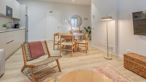En modern lägenhet med kök, matplats och ett vardagsrum med soffa och golvlampa.