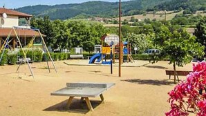 A playground with swings, a slide, and a table tennis table.