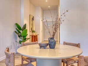A round dining table with wicker chairs, a vase with dried flowers, and a potted plant. - Modern studio near marina - guests (Estepona)