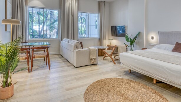 Una habitación de hotel moderna con cama, sofá, mesa de comedor y sillas.