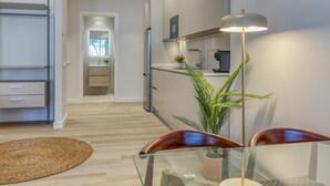Una cocina moderna con horno empotrado, cafetera y comedor con mesa y sillas de vidrio.