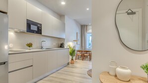 Una cocina moderna con horno empotrado, cafetera y zona de comedor con mesa y sillas.