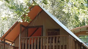 A wooden cabin with a balcony, surrounded by trees. - Mobile home with air conditioning - 6 guests (Saint-Point)