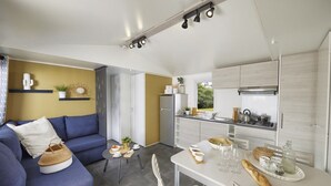 A modern kitchen with a dining area, a sofa, and a small table with food and drinks. - Mobile home with air conditioning - 6 guests (Saint-Point)