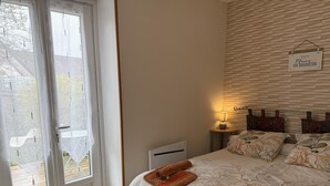 A bedroom with a bed, a nightstand, a lamp, a window with a view, and a sign on the wall. - Peaceful cottage, parking, pets allowed (Saint-Georges-sur-Cher)