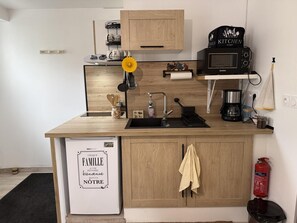 Une cuisine compacte équipée d’un four à micro-ondes, d’une machine à café et d’un petit réfrigérateur.