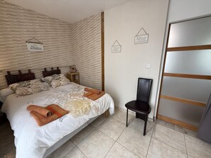 Une chambre à coucher avec un lit, une chaise, une table de chevet et un mur orné d’une inscription.