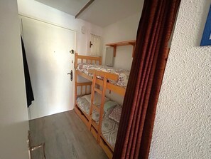 Ein Zimmer mit einem Etagenbett, einer Tür und einem Vorhang.