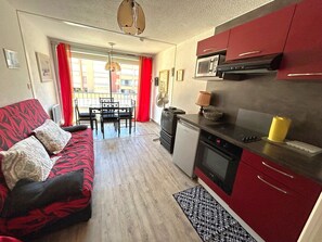 Ein kompakter Wohnraum mit einer Küchenzeile, einem Essbereich und einem Sofa.
