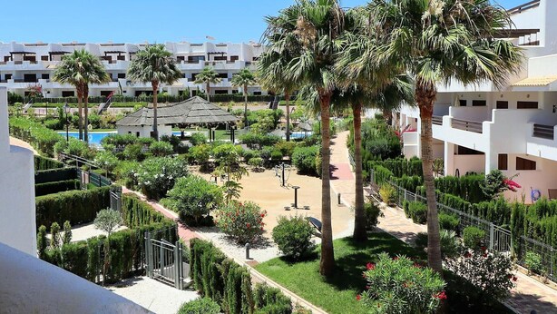 A resort with multiple white buildings, palm trees, a pool, and well-maintained gardens. - Bright apartment with AC - 6 guests (San Juan de los Terreros)