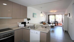 A modern kitchen with a dishwasher, stove, and sink. There is a dining area with a table and chairs. - Bright apartment with AC - 6 guests (San Juan de los Terreros)