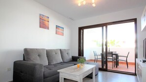 A living room with a grey sofa, a wooden coffee table, and a dining area with chairs and a table. - Bright apartment with AC - 6 guests (San Juan de los Terreros)