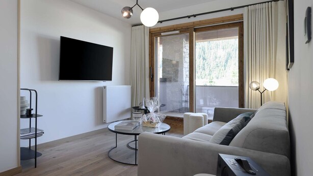 Ein modernes Wohnzimmer mit einer Couch, einem Couchtisch, einem an der Wand montierten Fernseher und einem Kamin.