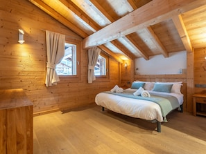 A wooden cabin bedroom with a bed, two windows with curtains, a wooden ceiling, and a small bedside table. - Cozy apartment, Wi-Fi - 6 guests (Les Gets)
