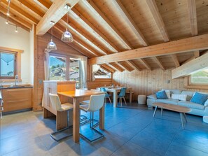 A modern interior with a wooden ceiling, a dining area, a kitchen, and a living space. - Spacious apartment with Wi-Fi - 6 guests (Les Gets)