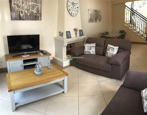 Un salon comprenant une télévision, un canapé, une table basse, une cheminée et des œuvres d’art accrochées aux murs.