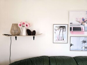 A wall-mounted shelf with decorative items, a framed beach scene, and a green couch. - Cozy Villa in Biscarrosse with Heated Pool, Close to Center, Sleeps 9 (Biscarrosse)