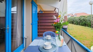Un balcón con una mesa para dos, una planta en maceta y vistas a una zona residencial.