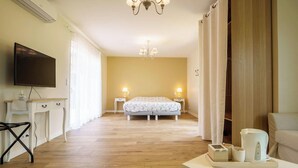 A hotel room with a bed, bedside lamps, a TV, a desk, and a coffee table. - 5-star villa, heated pool, 4 rooms with private baths and BBQ - Up to 12 guests (Parentis-en-Born)