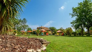 A large house with a tiled roof, surrounded by a well-maintained lawn and several outdoor umbrellas. - 5-star villa, heated pool, 4 rooms with private baths and BBQ - Up to 12 guests (Parentis-en-Born)