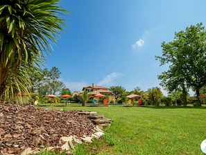 A large house with a tiled roof, surrounded by a well-maintained lawn and several outdoor umbrellas. - 5-star villa, heated pool, 4 rooms with private baths and BBQ - Up to 12 guests (Parentis-en-Born)