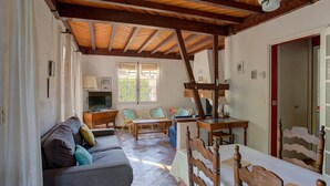 A room with a wooden ceiling, a sofa, a dining table, and a chair. - Charming 2-bedroom house with garden near the lake, perfect for holidays (Sanguinet)