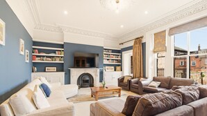 Ein Wohnzimmer mit Kamin, Sofas, einem Couchtisch und Bücherregalen.