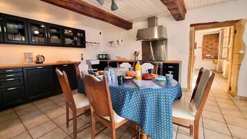 Une cuisine avec une table à manger, des chaises et un téléviseur.