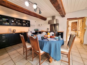Une cuisine avec une table à manger, des chaises et un téléviseur.