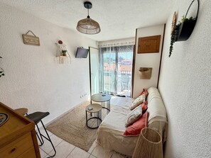 A cozy room with a bed, a small table, a TV, and a window with a view. - Bright apartment, pool view, parking - 4 guests (Argelès-sur-Mer)
