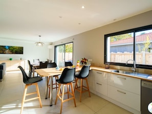 A modern kitchen with a dining area, large windows, and a view of the outside. - Charming Villa in Biscarrosse with Garden, 3 Bedrooms, and Terrace - Perfect for 6 Guests (Biscarrosse)