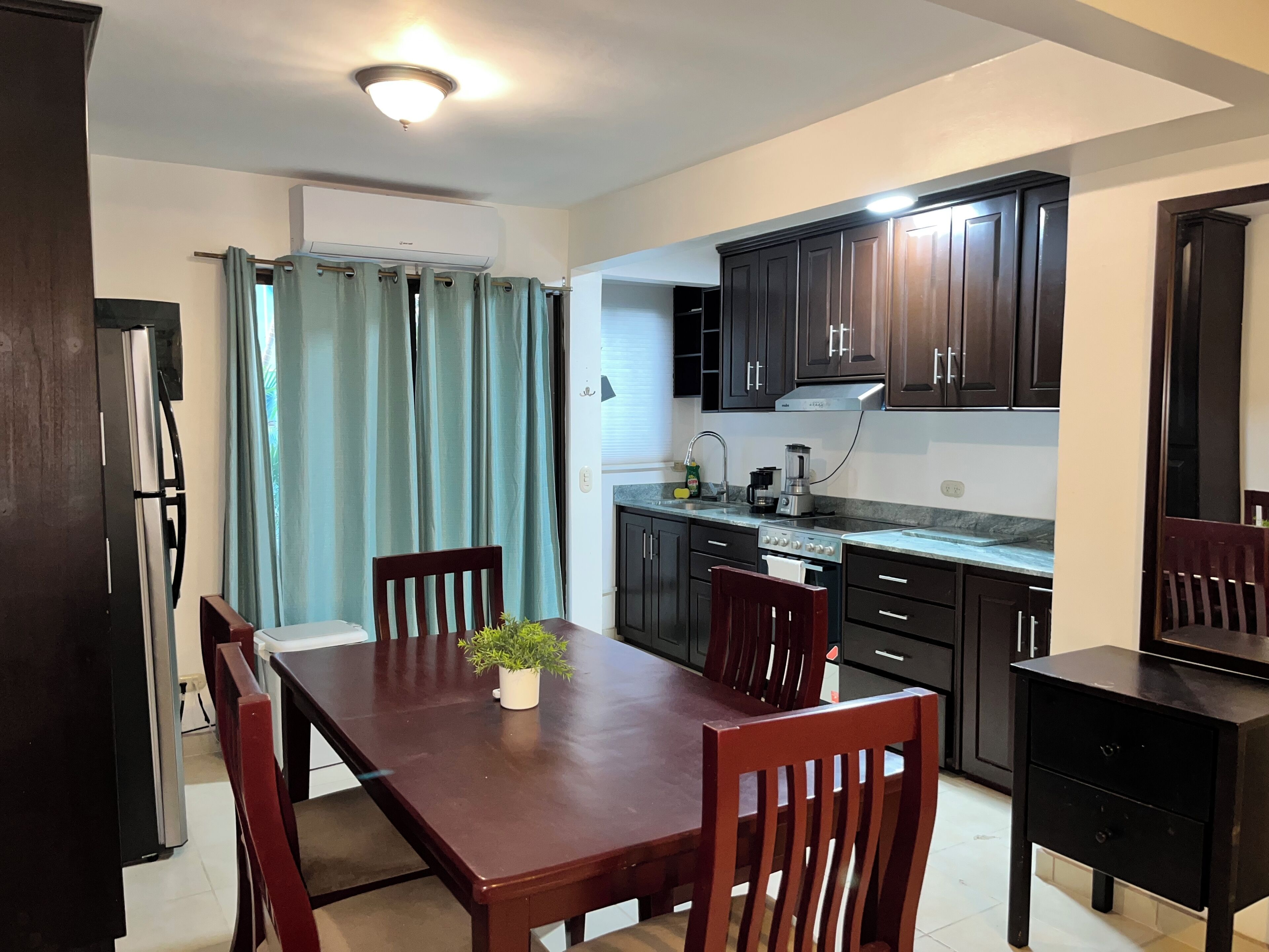 A compact kitchen with dark cabinets, a dining table with chairs, and a small countertop.
