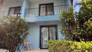 A two-story building with a balcony, a sliding glass door, and a small outdoor seating area. - This beautiful 2-bedroom, 2-bath condo is a true gem (Playas Del Coco)