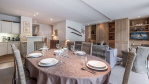 Un coin repas avec une table ronde dressée pour quatre personnes, entourée de chaises en osier.