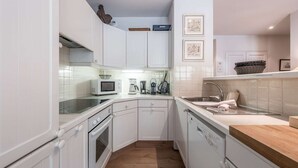 A compact kitchen with white cabinetry, a microwave, a coffee maker, and a dishwasher. - Charming apartment in resort centre - 6 guests (Courchevel 1550)